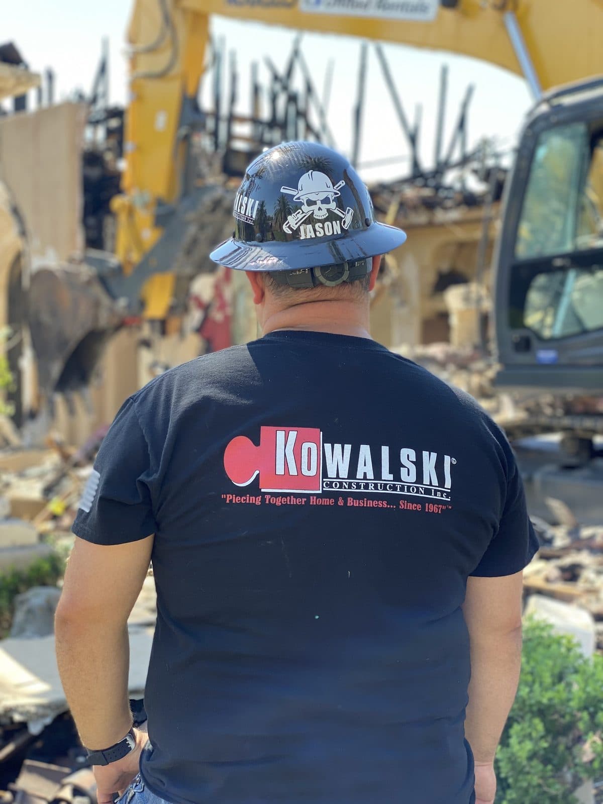 A Kowalski Construction crew member in branded gear surveying a fire-damaged property in Phoenix